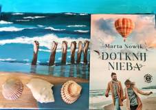 Książka Dotknij nieba, obok książki obraz morza.