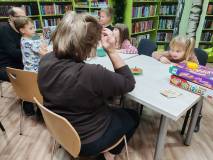 Uczestnicy spotkania zebrani wokół stołu, na swoją kolej czekają gry „Krzesła” i „Gorący ziemniak”
