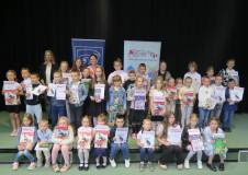 Najlepsi czytelnicy powiatu koszalińskiego stoją w grupie w towarzystwie zastępcy dyrektora bibliote