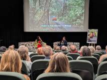 Widok ze strony: na scenie siedzi autorka Katarzyna Bellingham (po lewej) i prowadząca. Nad nimi na 