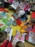 Przedszkolaki przeglądają książki, przygotowane przez bibliotekarkę