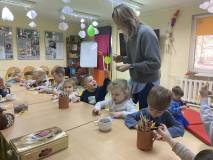 Dzieci przy stolikach kolorują zakładki 