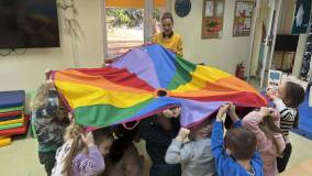 Dzieci wraz z bibliotekarką bawią się chustą animacyjną