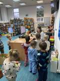 dzieci wypożyczają samodzielnie książkę przy pomocy bibliotekarza, skanując kod kreskowy 