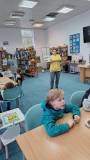 Bibliotekarka pokazuje dzieciom książkę o dokarmianiu ptaków 