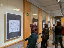 Uczestniczka po prawej przygląda się wiszącemu wydrukowi ekslibrisu po lewej.