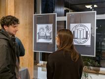 Dwoje uczestników dyskutuje o pracach znajdujących się pomiędzy nimi.