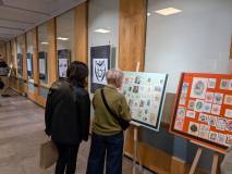 Dwie uczestniczki po lewej przyglądają się wystawie archiwalnych ekslibrisów, przyklejonych do karto