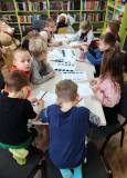 Grupa „Wiewiórek” przy stołach rozwiązuje zagadkę logiczną