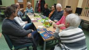 Na zdjęciu widać omawianą książkę i dyskutujących przy stole uczestników DKK.