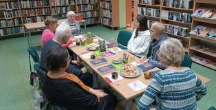 Uczestnicy spotkania siedzą przy stole i rozmawiają na temat książki.
