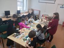 Bibliotekarka pokazuje dzieciom jak wykonać pracę plastyczną