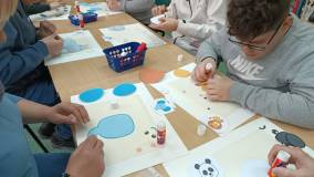 Uczestnicy przyklejają na kartce papieru fragmenty zwierząt. 