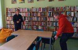 Uczestnicy ustawiają stoły w czytelni.