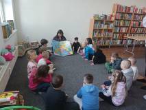 Bibliotekarka pokazuje dzieciom, gdzie na mapie jest ojczyzna pizzy