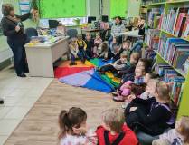 Bibliotekarka pokazuje dzieciom książki o kotach