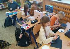 Dzieci wycinają pandę i naklejają elementy na talerzykach jednorazowych.