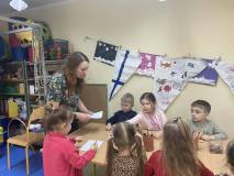 Bibliotekarka rozdaje dzieciom śnieżynki do rysowania po śladzie