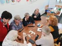 Uczestniczki klubu gier planszowych układają domino w bibliotece na stole.