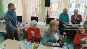 Wiceprzewodniczący Ikara wręcza paniom kwiatki.