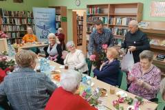 Panowie wręczają kwiaty i prezenty paniom. 