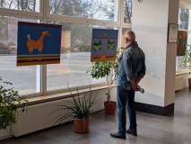 Jasne wnętrze galerii sztuki. Mężczyzna w dżinsowej koszuli stoi tyłem do obiektywu, oglądając dwa o