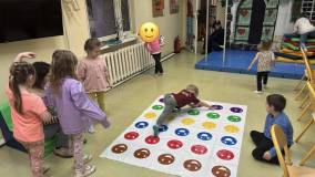 Dzieci w trakcie zabawy. Chłopiec jest na macie i sięga rączkami i nóżkami na różne kolorowe pola