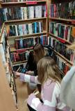 Bibliotekarka pomaga włączyć książkę do działu Sensacja.