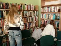 Uczniowie ustawiają książki w poszczególnych działach biblioteki.