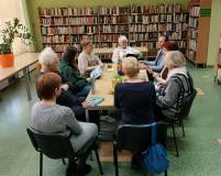 Uczestnicy spotkania siedzą przy stole i rozmawiają na temat książki.