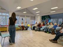 Zdjęcie wykonano zza pleców prowadzącej (widoczna sylwetka kobiety w ciemnej koszulce i jeansach po 