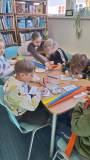 dzieci wykonują pracę plastyczną przy stole