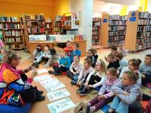 Na zdjęciu dzieci siedzą na podłodze, przed nimi ułożone są plansze z nazwami emocji, o których pier