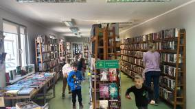 Dzieci podczas zabawy w szukanie zwiastunów wiosny między bibliotecznymi regałami