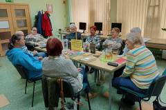 Dyskusja o książkach, na stole stoi dzbanek z herbatą oraz leżą książki.