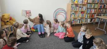 Bibliotekarka czyta książkę, a dzieci siedzą na dywanie 