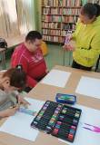 Bibliotekarka pomaga uczestnikowi w wykonaniu zakładki. 