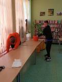Uczestnicy wycierają stoły i wykonują prace porządkowe w czytelni.