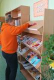 Uczestnik wyciera szmatką regał z czasopismami. 