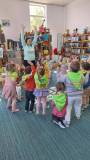dzieci bawią się z bibliotekarką w ziemię i niebo. wyskakują w górę