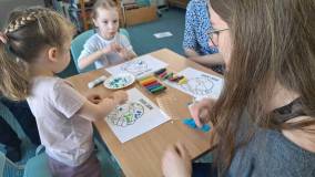 dzieci wykonują pracę plastyczną przy stole