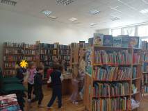 Dzieci podczas zabawy integracyjnej miedzy bibliotecznymi regałami
