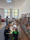Dzieci stoją przy stolikach i wykonują prace plastyczną