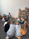 Bibliotekarka pokazuje dzieciom książkę, dzieci siedzą na dywanie