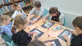 dzieci wykonują pracę plastyczną przy stole 