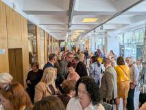Spotkanie kuluarowe
Zdjęcie przedstawia jasny, nowoczesny korytarz biblioteczny wypełniony ludźmi.