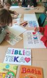 Na stole kartki z napisem Biblioteka, obok książki, kredki i mazaki.