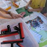 Dziecko i osoba dorosła wybierają kolorowe elementy LEGO DOTS oraz układają je na zielonej płytce ko