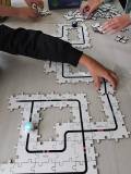 Na stoliku gra puzzle z mini-robotem przemieszczającym się po układance
