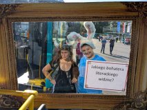 Dwie osoby pozują za ozdobną ramą z napisem „Jakiego bohatera literackiego widzisz?”. Jedna ma opask